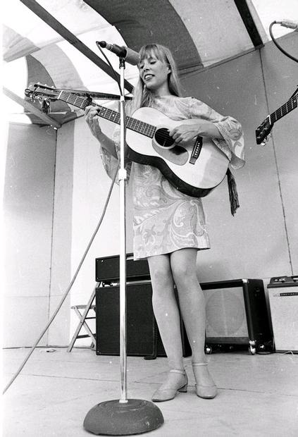 Joni performing on stage in a paisley patterned dress. Photo by Hayashi.